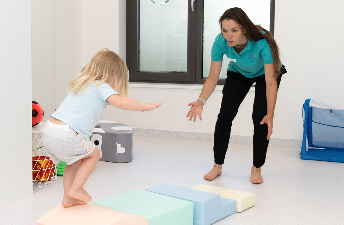 Mini Maxi Med – interdisziplinäre Therapie Mini Maxi Med Physiotherapeutin im spielerische Bewegungsangebot mit Kind
